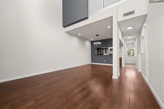 a view of large space with wooden floor and a kitchen
