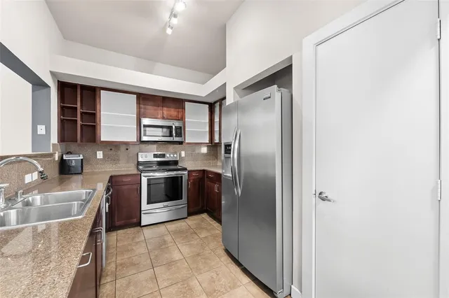 a kitchen with stainless steel appliances granite countertop a refrigerator a sink a stove top oven and a dishwasher