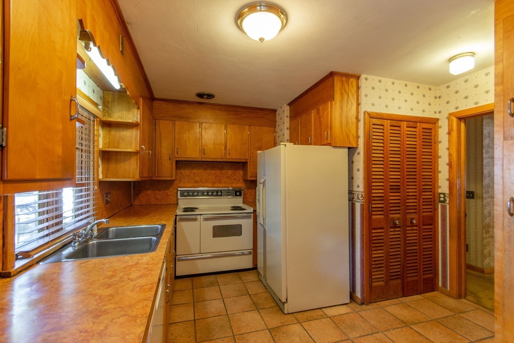 182 Dayton Street Springfield, MA 01118 - Photo 17 of 30 a kitchen with a refrigerator a stove top oven and cabinets