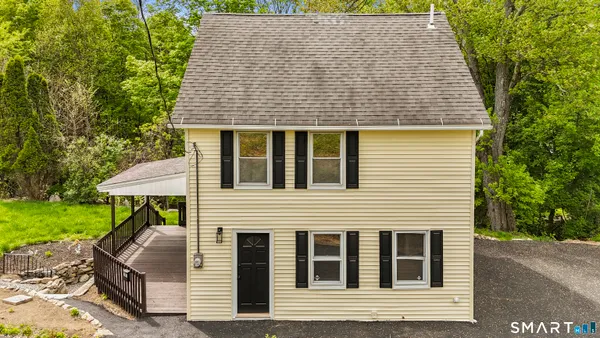 a front view of a house with garden and trees