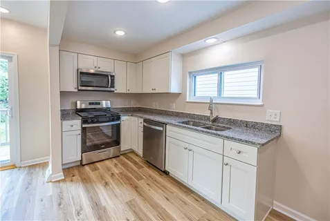 a kitchen with granite countertop a sink cabinets and stainless steel appliances