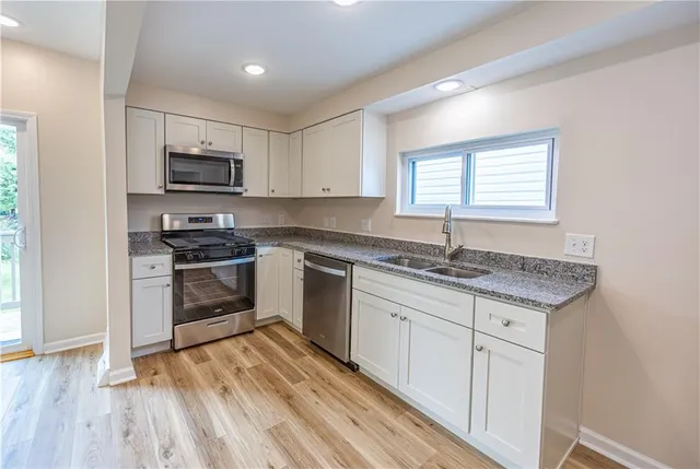 a kitchen with granite countertop a sink cabinets and stainless steel appliances