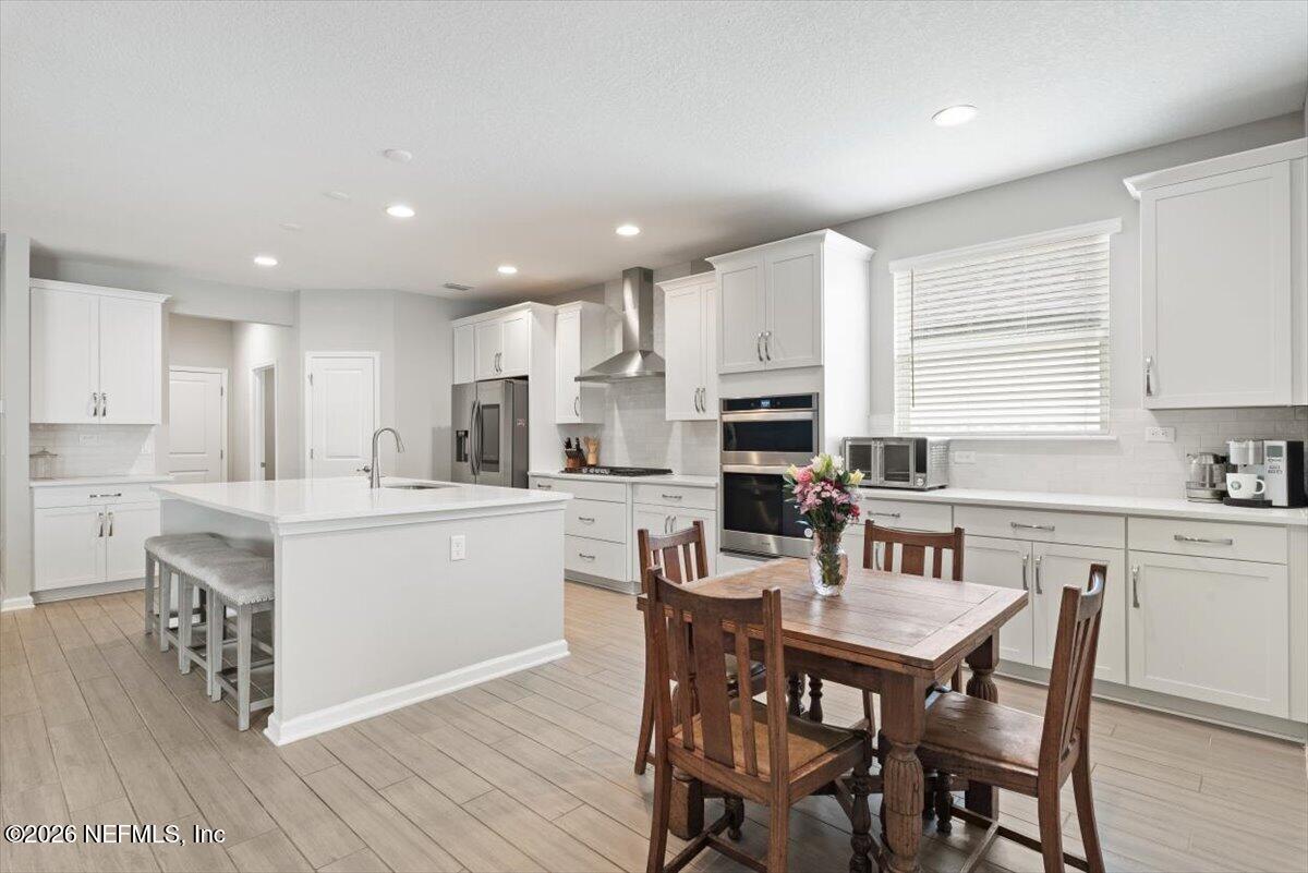 553 Archstone Way St. Augustine, FL 32092 - Photo 16 of 56 a kitchen with a table chairs a sink dishwasher a stove a microwave oven and a dining table with wooden floor