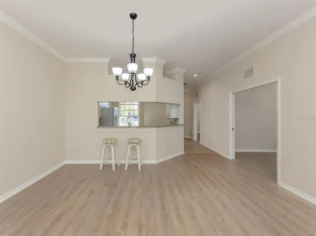 a view of a room with wooden floor chandelier and windows
