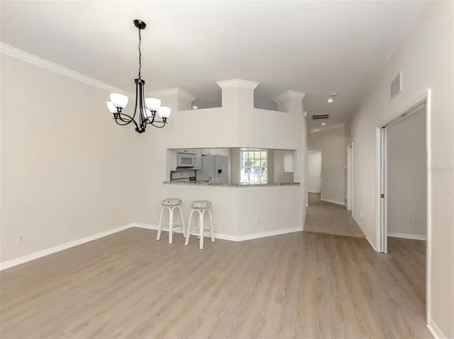 a view of a room with wooden floor chandelier and windows