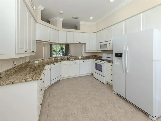 a kitchen with granite countertop white cabinets and white appliances