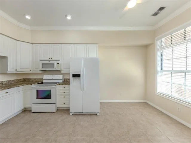 a kitchen with stainless steel appliances granite countertop white cabinets and window