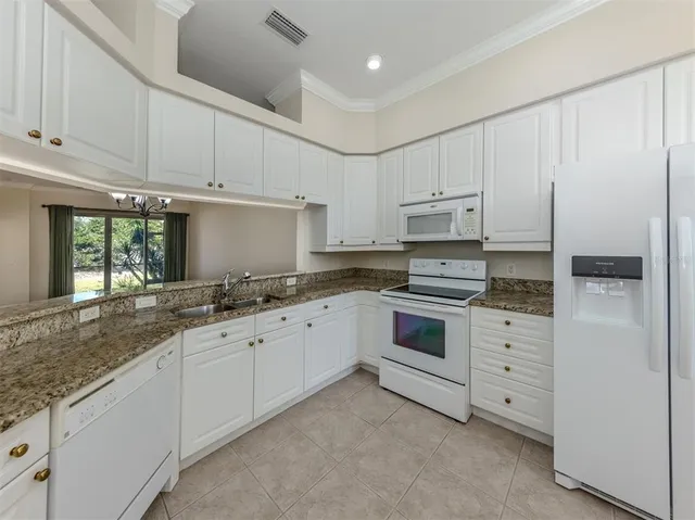 a kitchen with granite countertop white cabinets and white appliances