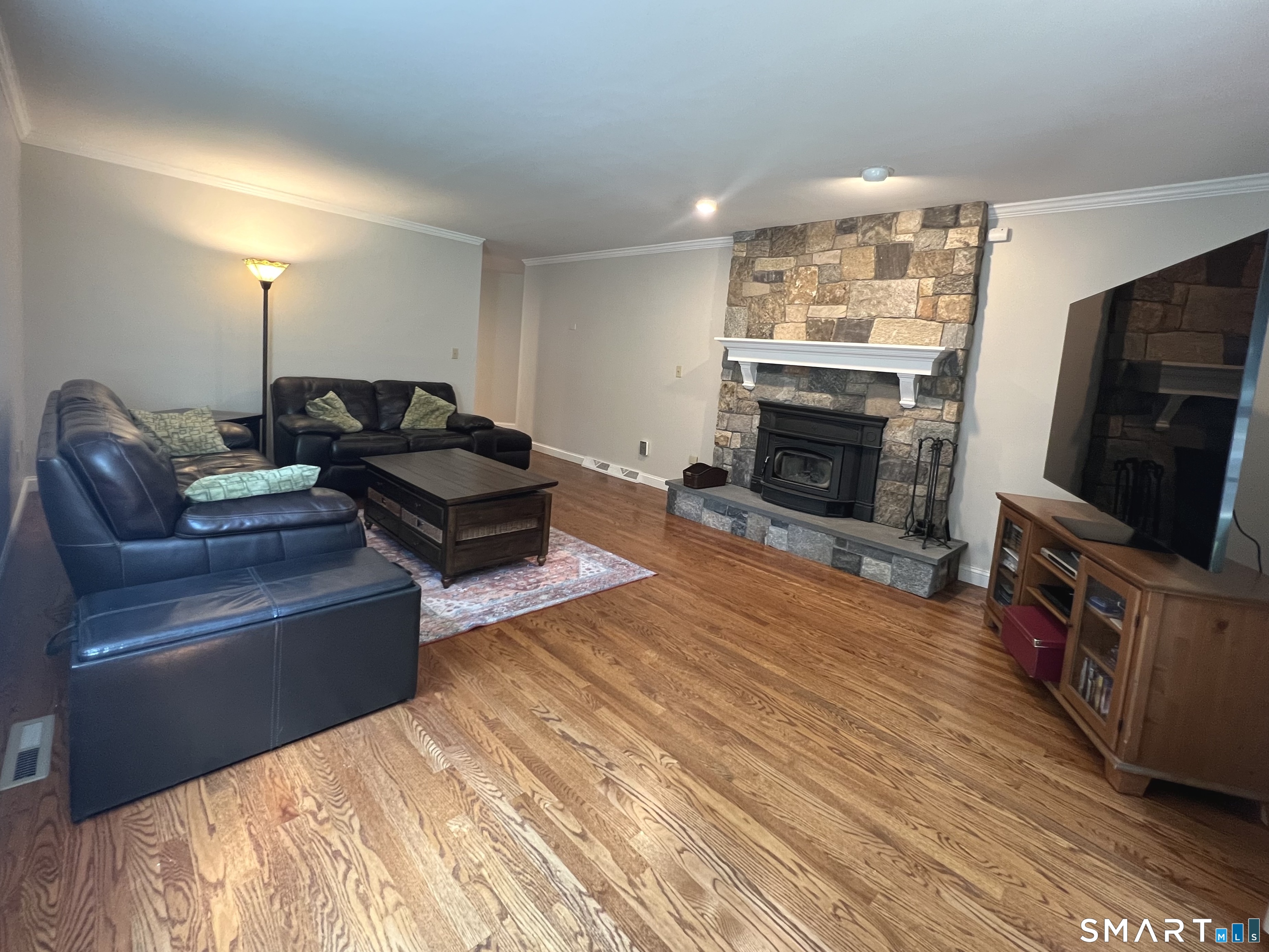 60 West Meadow Road Hamden, CT 06518 - Photo 14 of 37 Spacious family room with gleaming hardwood floors, fresh neutral paint, and a stone fireplace with a wood-burning insert that keeps the room warm and cozy.