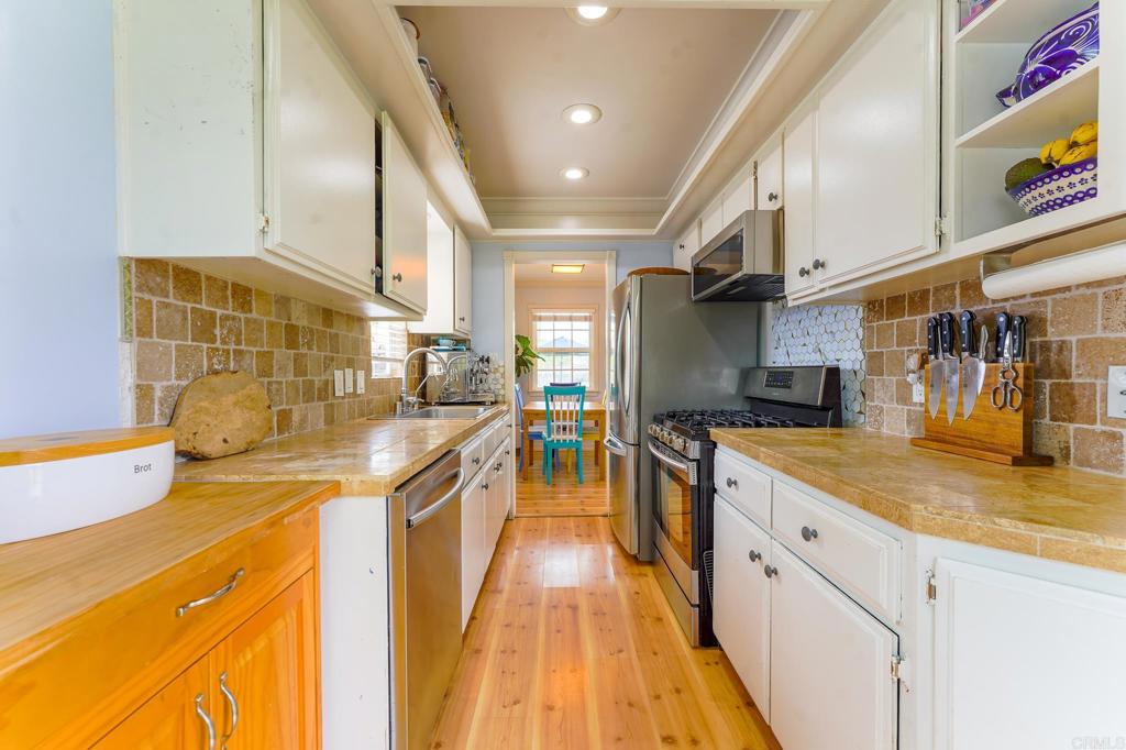 1043 Aloha Drive Encinitas, CA 92024 - Photo 17 of 27 a kitchen with stainless steel appliances granite countertop a sink and wooden cabinets