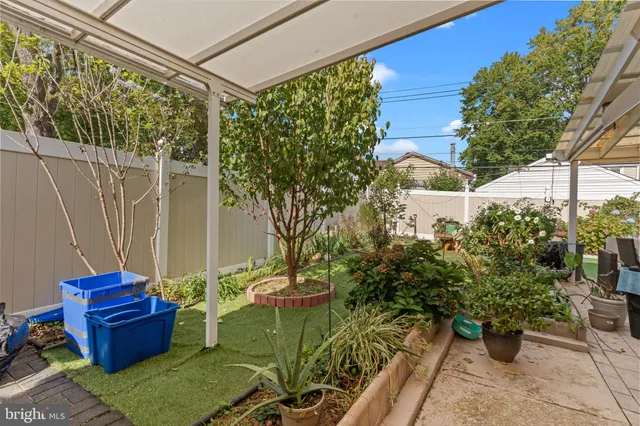 a view of a white house next to a yard with big trees