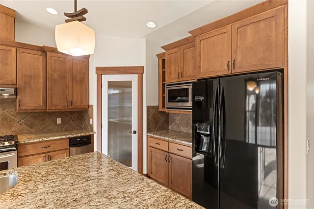a open kitchen with stainless steel appliances granite countertop a stove and a large refrigerator