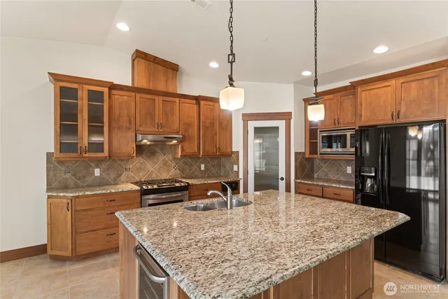 a kitchen with granite countertop kitchen island stainless steel appliances a sink stove and cabinets