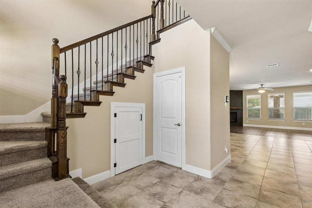 537 Hunt Farms Road Fate, TX 75189 - Photo 4 of 36 Carpeted staircase with wood newel posts and wrought iron balusters, tiled flooring, wood-finish flooring, and a ceiling fan with integrated lighting