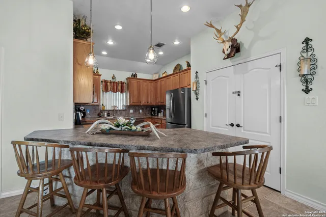 a kitchen with a table chairs refrigerator and wooden floor