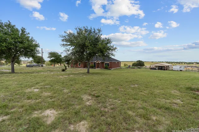 a view of a green field with tree in the background