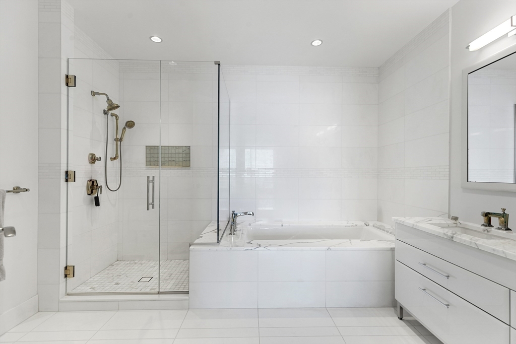 22 Liberty Drive, Unit 10D Boston, MA 02210 - Photo 15 of 26 a bathroom with a granite countertop bathtub shower sink and mirror