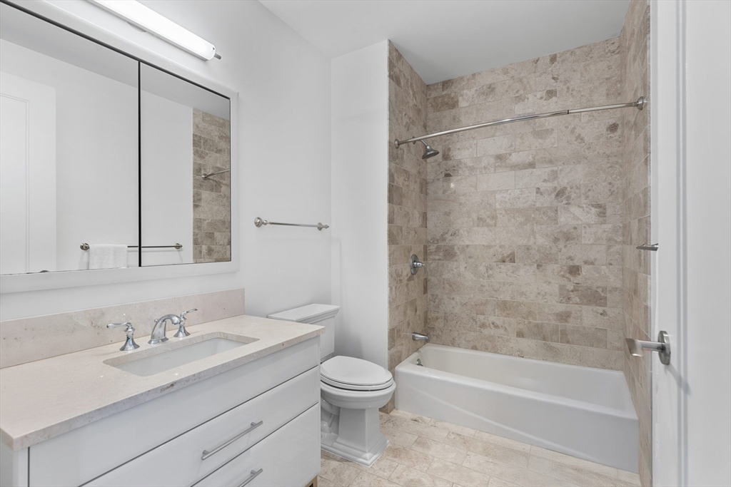 22 Liberty Drive, Unit 10D Boston, MA 02210 - Photo 19 of 26 a bathroom with a granite countertop sink toilet a shower and a mirror