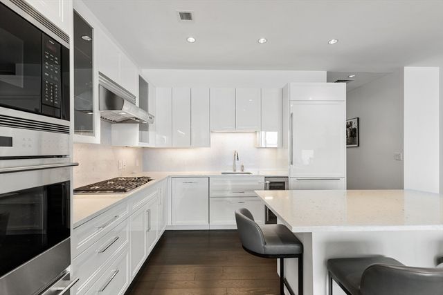 a kitchen with granite countertop white cabinets and stainless steel appliances