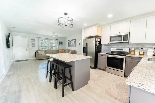 a kitchen with stainless steel appliances kitchen island granite countertop a table chairs in it and wooden floors