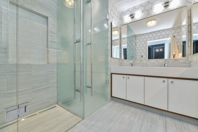 a spacious bathroom with a double vanity sink a mirror and shower