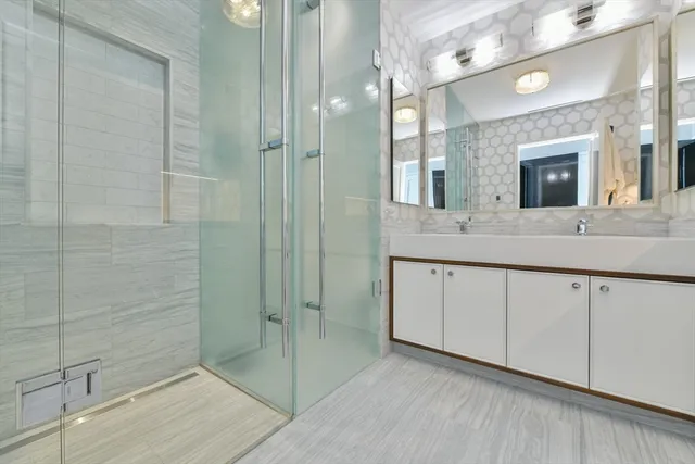 a spacious bathroom with a double vanity sink a mirror and shower