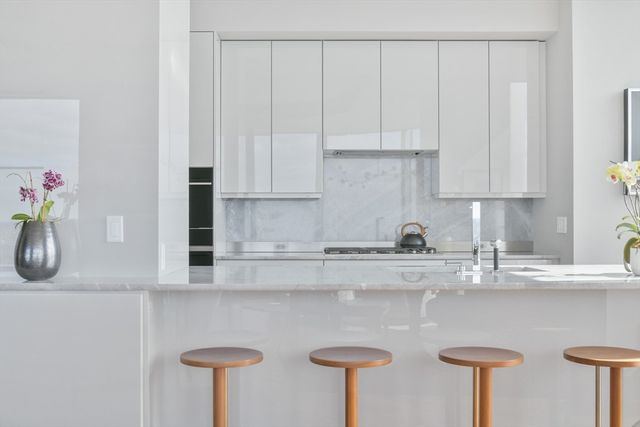 a kitchen with stainless steel appliances granite countertop a sink a stove and white cabinets