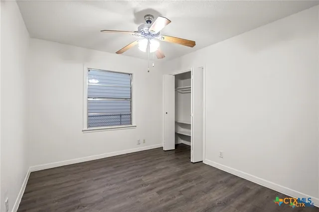 an empty room with a window and a fan