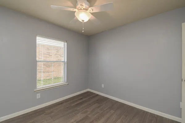 an empty room with a window and wooden floor
