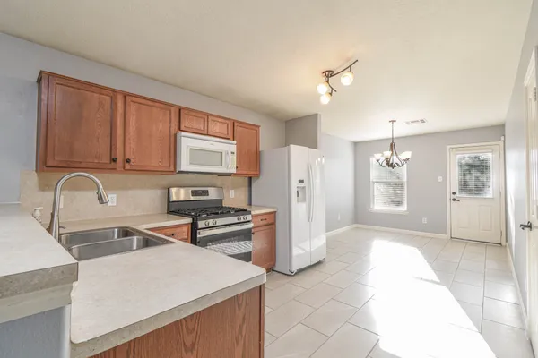 a kitchen with stainless steel appliances granite countertop a stove a sink dishwasher and a refrigerator with wooden cabinets