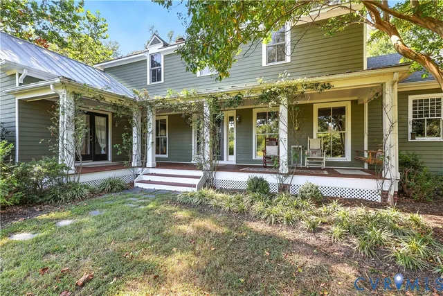 front view of a brick house with a large window and potted plants