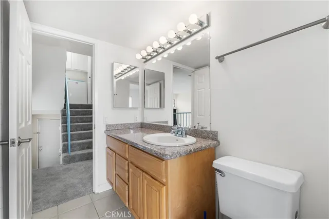 a bathroom with a granite countertop sink a toilet a mirror and shower