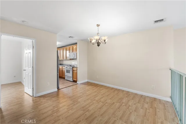 a view of a hallway with wooden floor and a kitchen