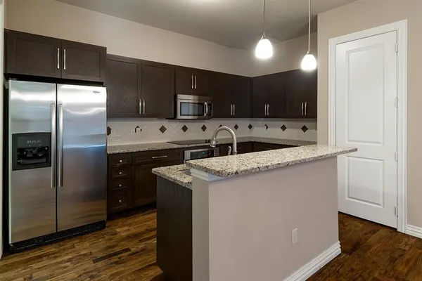 a kitchen with stainless steel appliances granite countertop a sink a refrigerator and a microwave