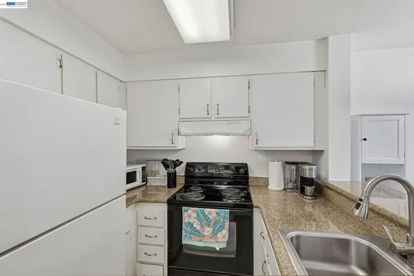 a kitchen with granite countertop white cabinets and stainless steel appliances