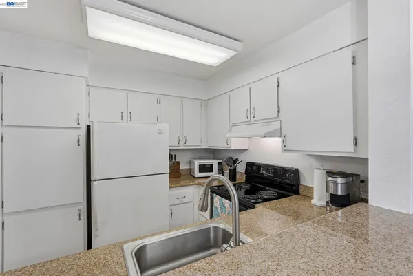 a kitchen with stainless steel appliances granite countertop a refrigerator sink stove and cabinets