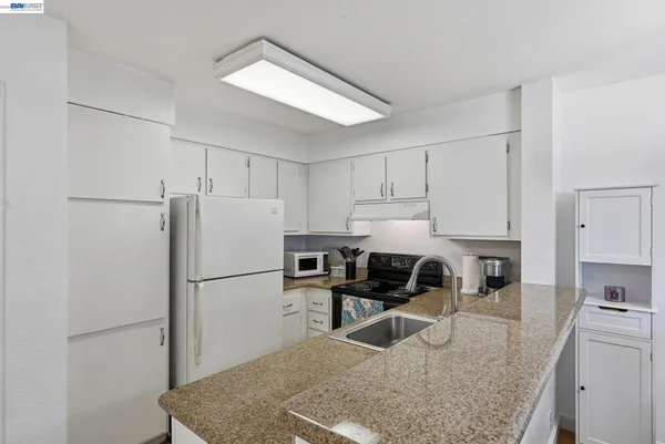 a kitchen with granite countertop a refrigerator and a sink