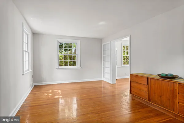 a view of an empty room with window and wooden floor
