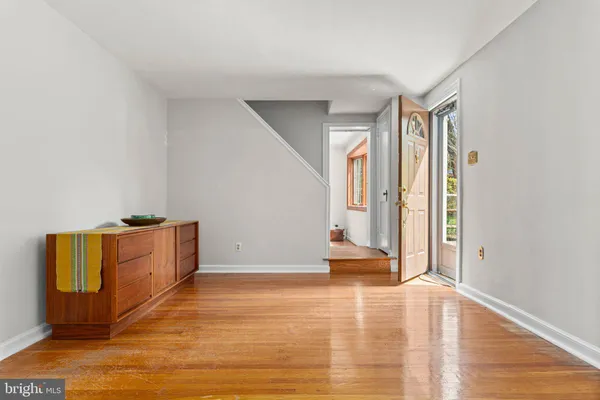 a view of an empty room with wooden floor and a window
