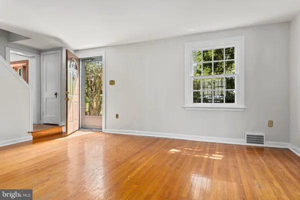 a view of an empty room with wooden floor and a window