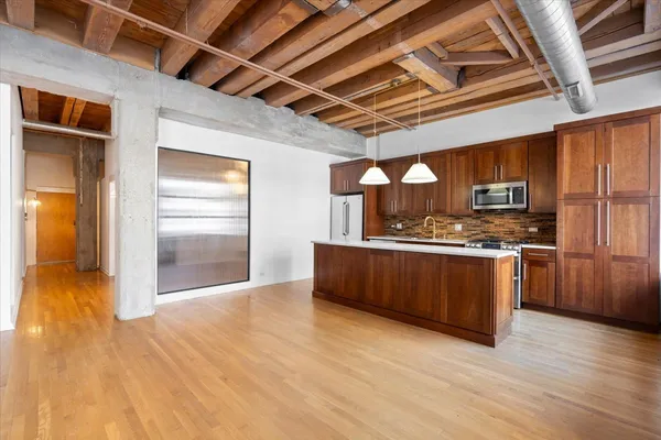 a view of kitchen with stainless steel appliances granite countertop a stove a refrigerator a sink with wooden floors and cabinets