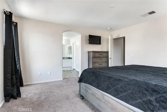 a bedroom with a bed and a flat tv screen on dresser