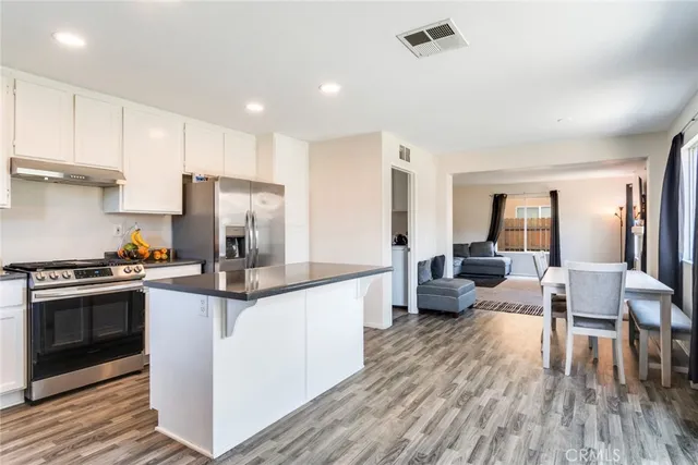 a kitchen with stainless steel appliances a stove a refrigerator a sink dishwasher and a dining table with wooden floor