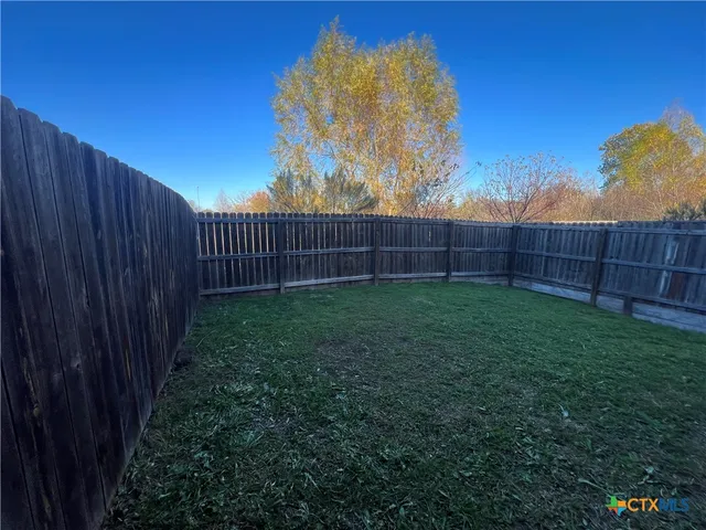 a view of a backyard with a fence and wooden fence