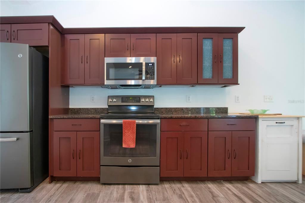 1422 Lightfoot Road Wimauma, FL 33598 - Photo 31 of 98 a kitchen with granite countertop wooden cabinets and stainless steel appliances