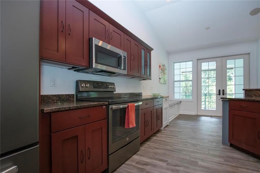 1422 Lightfoot Road Wimauma, FL 33598 - Photo 32 of 98 a large kitchen with stainless steel appliances granite countertop wooden cabinets a stove top oven with wooden floor