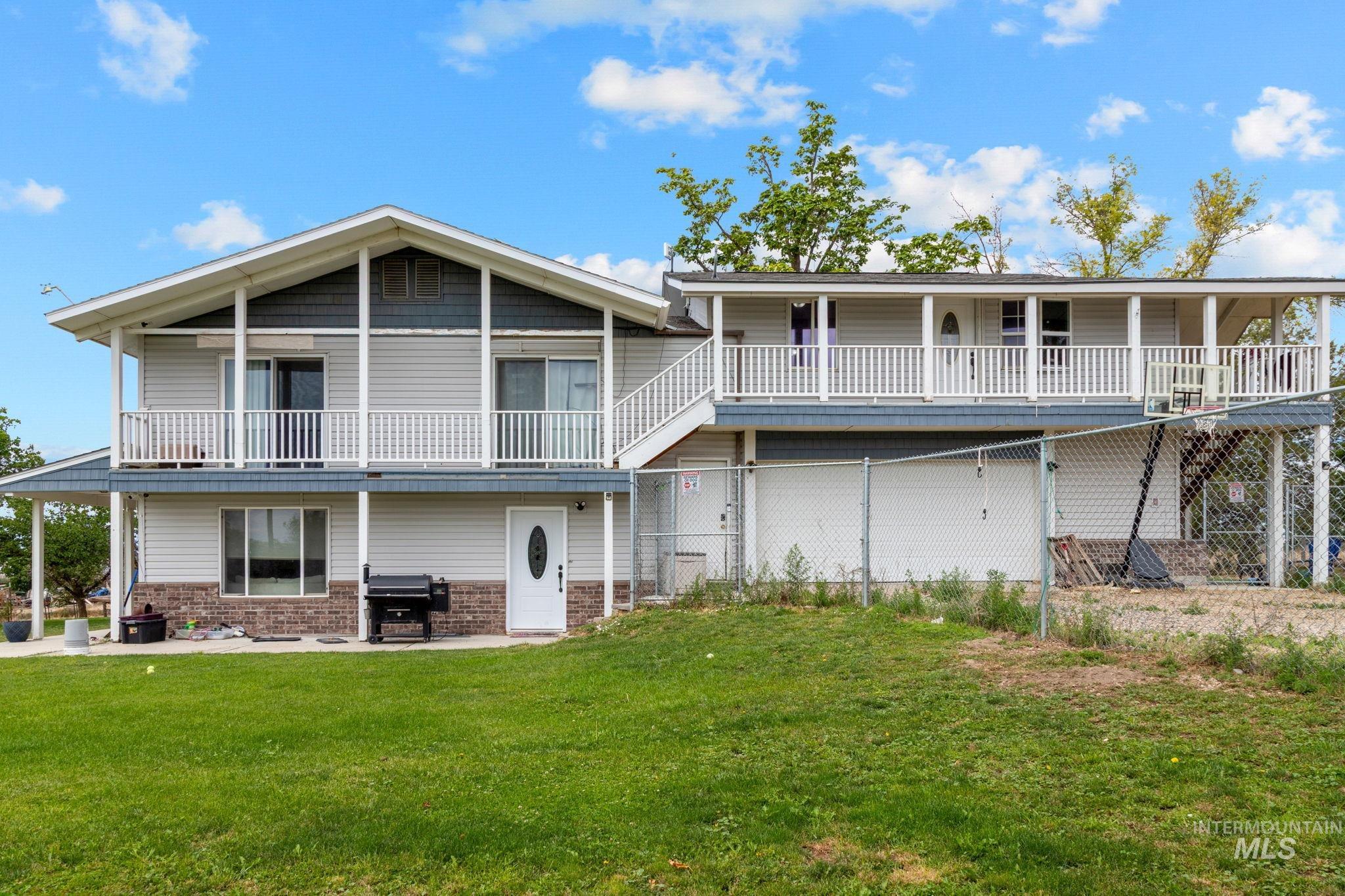 18338 Pride Lane Caldwell, ID 83607 - Photo 3 of 50 Two-story residence featuring light gray siding with brick-finish wainscoting, an upper-level balcony with white railings, and a covered patio below