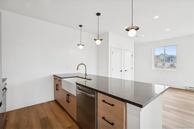 a kitchen with stainless steel appliances granite countertop a sink a stove and a wooden floors