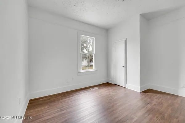 an empty room with wooden floor and windows