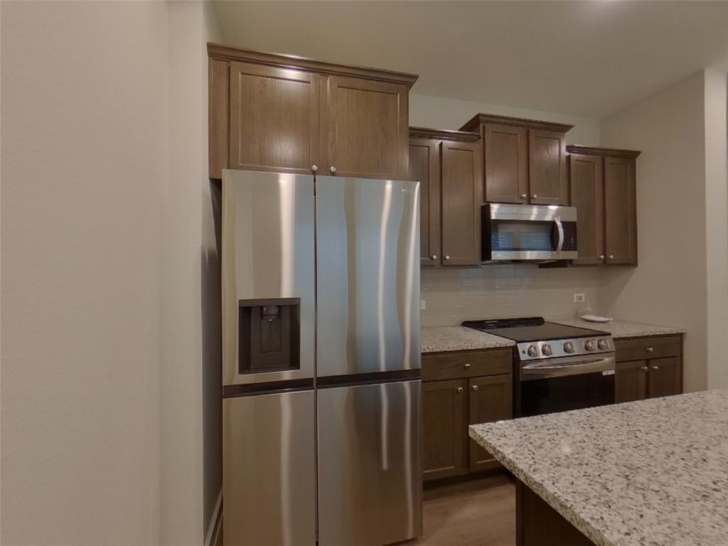 2545 Waddill Rivers Way McKinney, TX 75071 - Photo 2 of 9 a kitchen with stainless steel appliances a refrigerator and a stove top oven